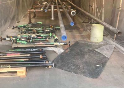 Pipe being abrasive blasted, there are a variety of different sized pipes including elbow pipes and pipes of different lengths and sizes which are use by industrial gas piping