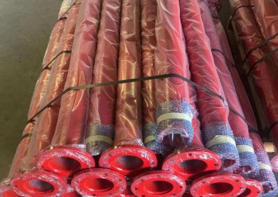 Straight gas pipes in standard length that have been abrasive blasted under-coated, surface coated a safety red colour wrapped in plastic ready for shipment