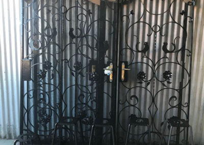 A set of 4 ornate gates and 4 stools that have been restored shown here with the the finishing black powder coating drying