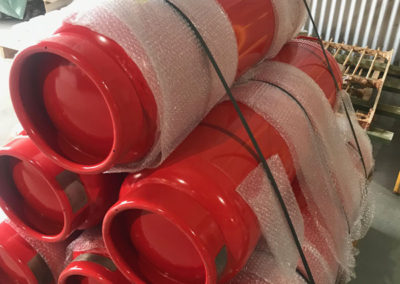 Industrial large fire extinguishers that have been resprayed red, loaded on a pallet ready for delivery